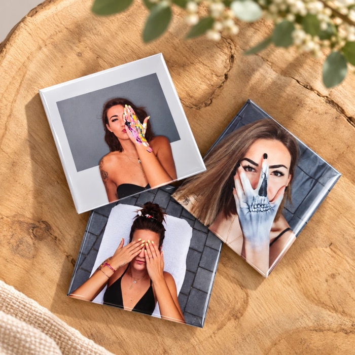 Drei Fotomagnete mit Porträtaufnahmen auf einem Holzteller
