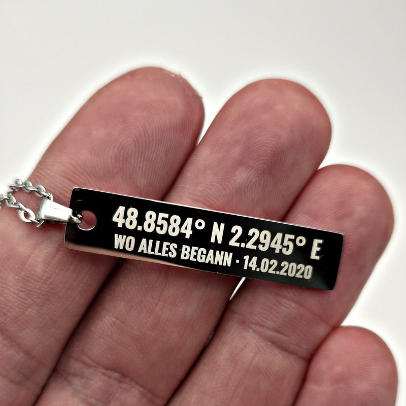 Gravierter Anhänger mit Koordinaten in der Hand