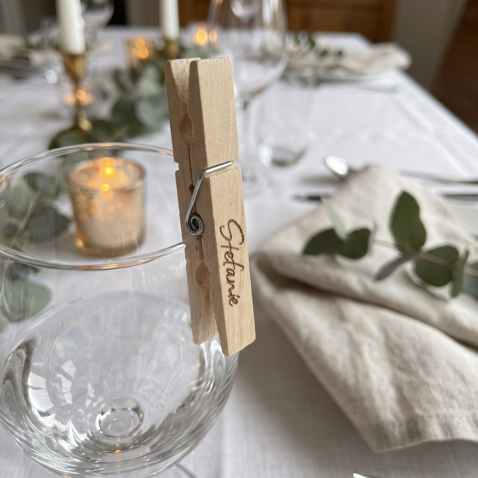 Wäscheklammer mit graviertem Namen als Platzkarte am Glasrand einer Hochzeitstafel